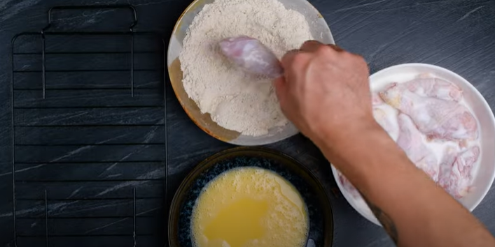 dredging a drumstick in egg mixture and flour