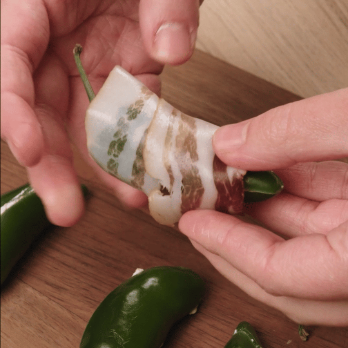 stuffed jalapeno being wrapped with bacon