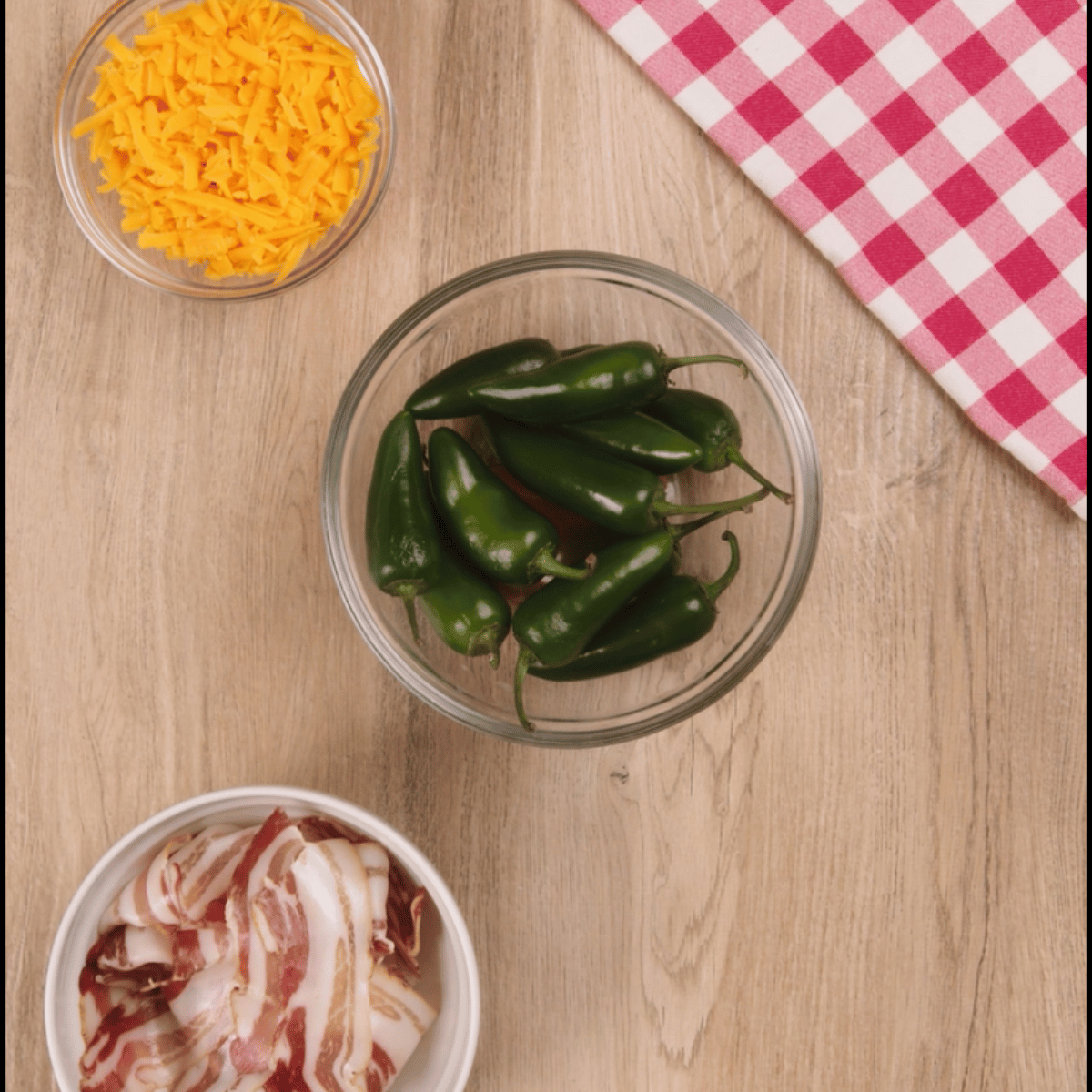 Overhead view of ingredients for bacon wrapped jalepeno poppers. Jalepenos, bacon, cheese